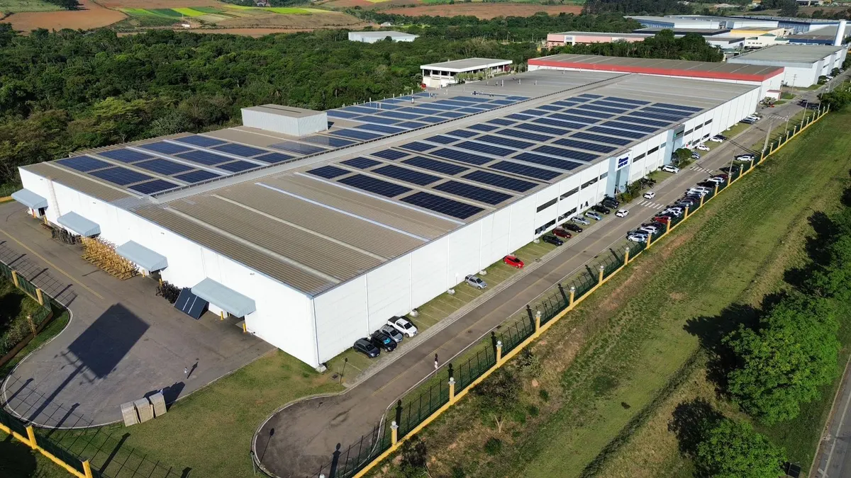 Galpão industrial da Acument com o telhado coberto de painéis solares, visto de drone