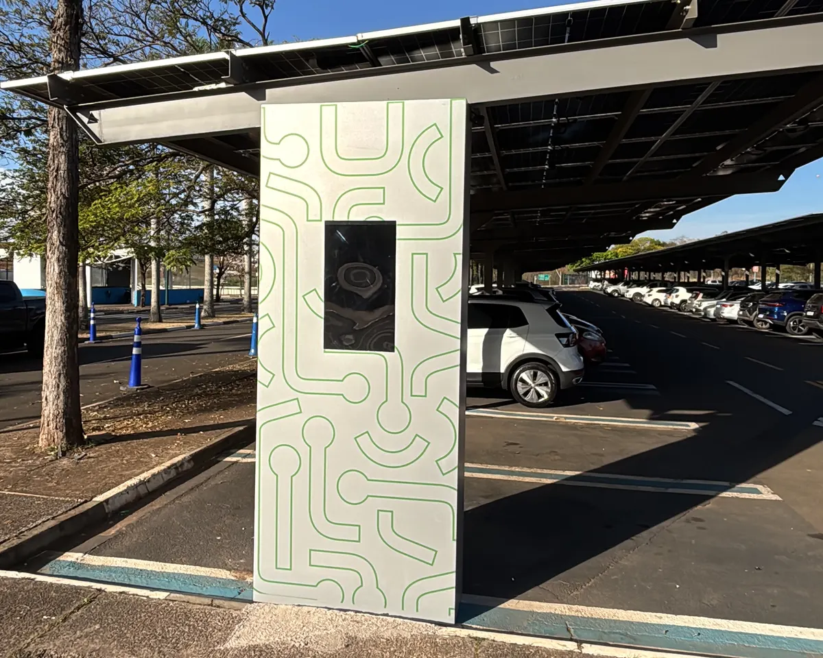 Totem de recarga de carro elétrico sob o carport solar do shopping, num estacionamento com carros nas vagas
