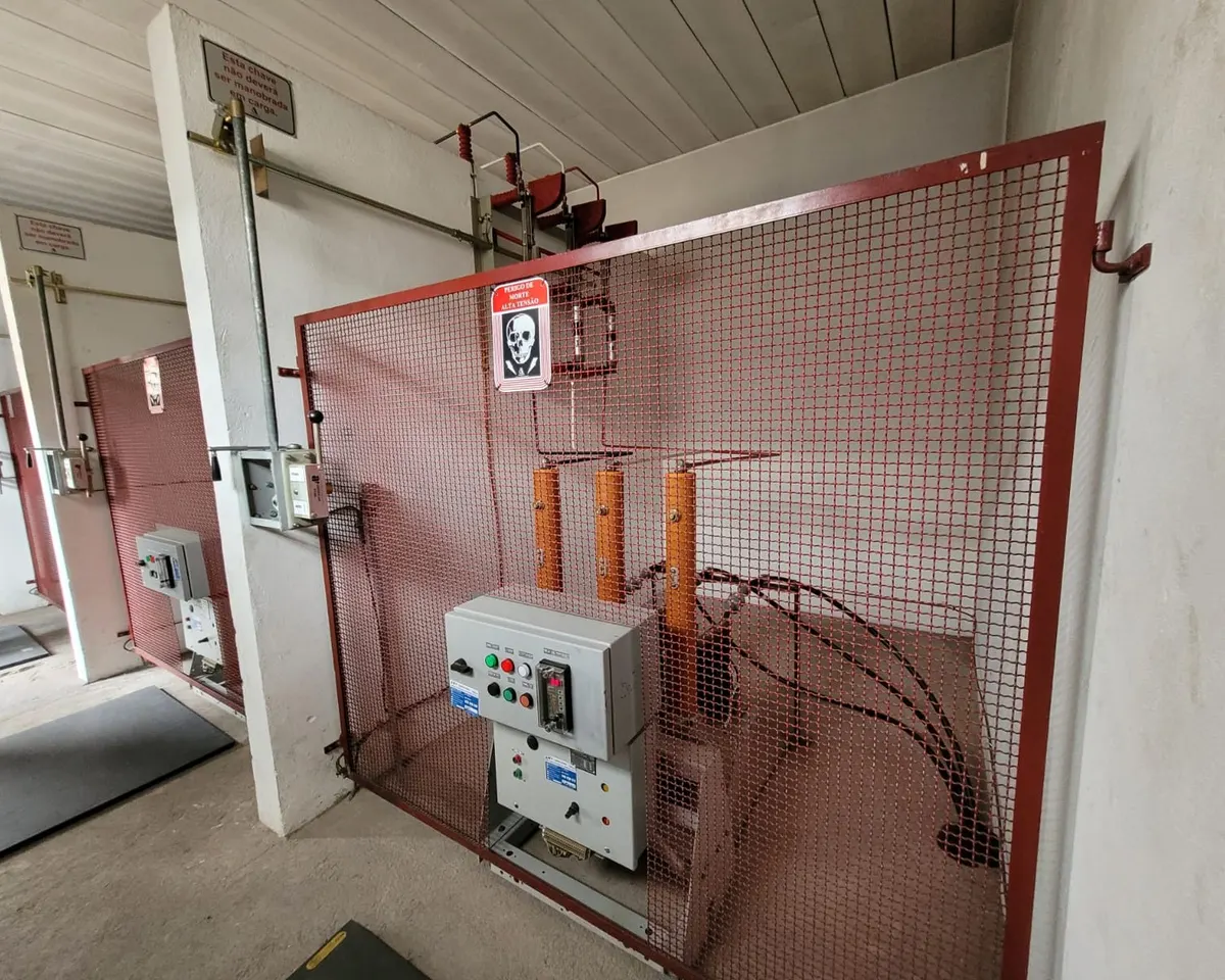 Cabine primária antiga com disjuntor de média tensão atrás da tela de proteção, vista em visita técnica da nossa engenharia